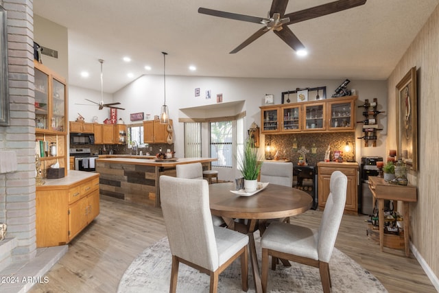 dining space featuring ceiling fan, light wood-type flooring, and vaulted ceiling