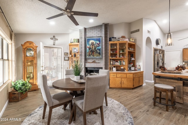 dining area featuring ceiling fan, lofted ceiling, a textured ceiling, and light hardwood / wood-style flooring