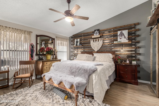 bedroom with a textured ceiling, ceiling fan, wood-type flooring, and vaulted ceiling