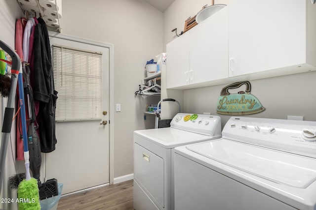 laundry area with washing machine and dryer, hardwood / wood-style floors, and cabinets