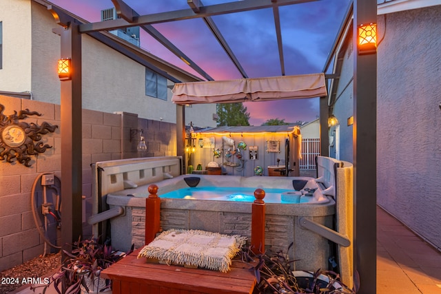 patio terrace at dusk featuring a hot tub