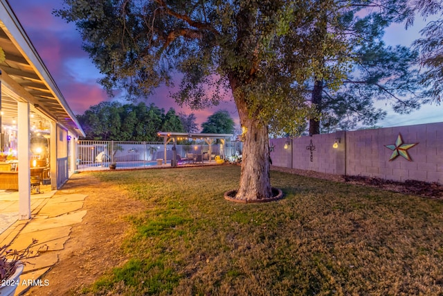 yard at dusk featuring a swimming pool