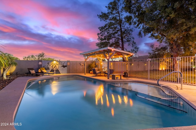 pool at dusk featuring a gazebo and a patio area