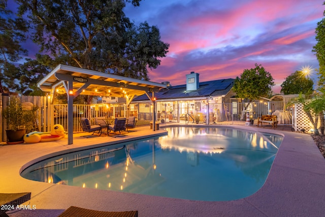 pool at dusk featuring a patio area