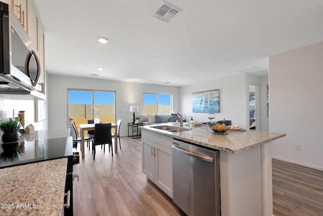 1234 N 13th St, Coolidge, AZ 85128 - kitchen featuring appliances with stainless steel finishes, wood finished floors, light stone countertops, recessed lighting, and an island with sink