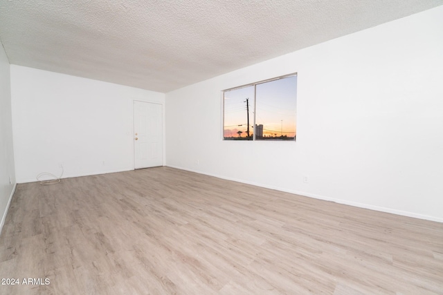 spare room featuring a textured ceiling and light wood-type flooring