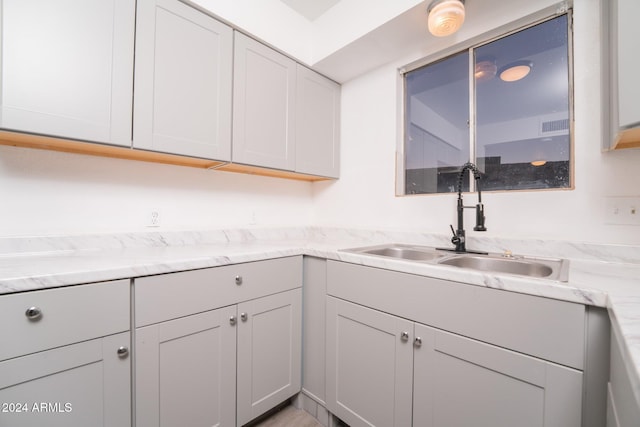 kitchen featuring light stone counters and sink