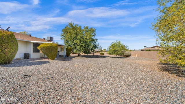 view of yard with central AC unit and fence