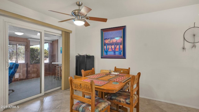 dining area featuring light tile patterned flooring, a ceiling fan, and baseboards