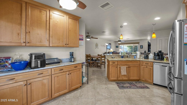 kitchen with a peninsula, a sink, visible vents, appliances with stainless steel finishes, and decorative light fixtures