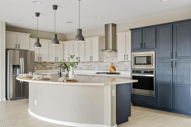 kitchen with an island with sink, a sink, stainless steel appliances, light countertops, and wall chimney range hood