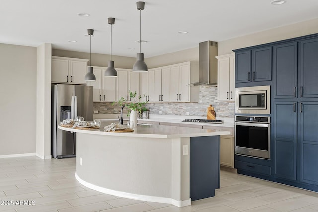 kitchen with an island with sink, a sink, stainless steel appliances, light countertops, and wall chimney exhaust hood