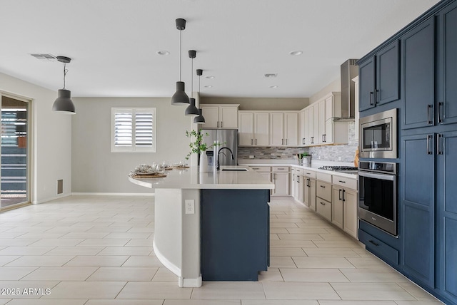 kitchen featuring tasteful backsplash, wall chimney range hood, decorative light fixtures, light countertops, and appliances with stainless steel finishes