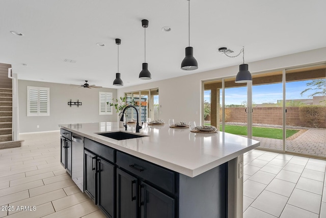 kitchen featuring a sink, a healthy amount of sunlight, an island with sink, light countertops, and stainless steel dishwasher