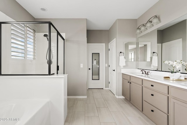 bathroom featuring baseboards, vanity, a garden tub, and a shower stall