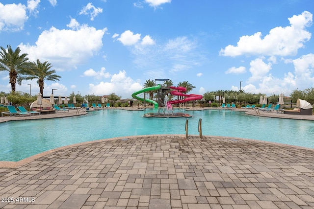 community pool with a patio, a water slide, and a water play area