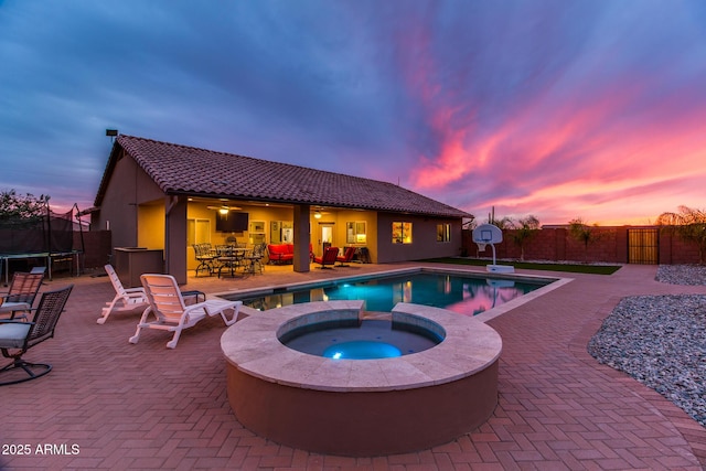 view of swimming pool featuring a fenced in pool, an in ground hot tub, a trampoline, fence, and a patio area