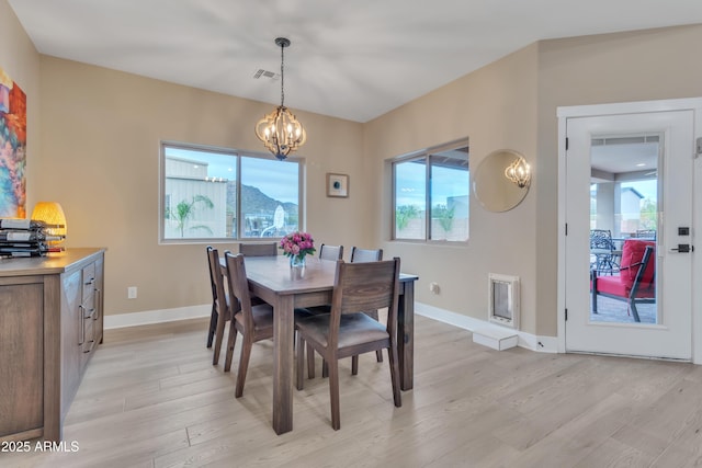 dining room with light wood-type flooring, an inviting chandelier, and baseboards