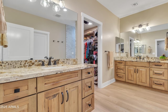 full bathroom featuring visible vents, two vanities, a sink, and wood finished floors