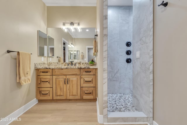 bathroom featuring wood finished floors, vanity, baseboards, and walk in shower