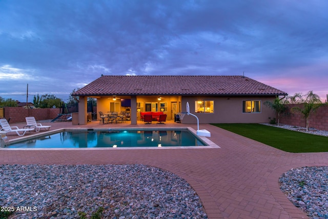 pool at dusk with a fenced in pool, a yard, a fenced backyard, and a patio