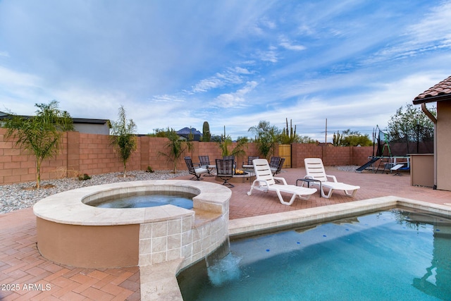 view of pool with a fenced in pool, a trampoline, a patio area, an in ground hot tub, and a fenced backyard