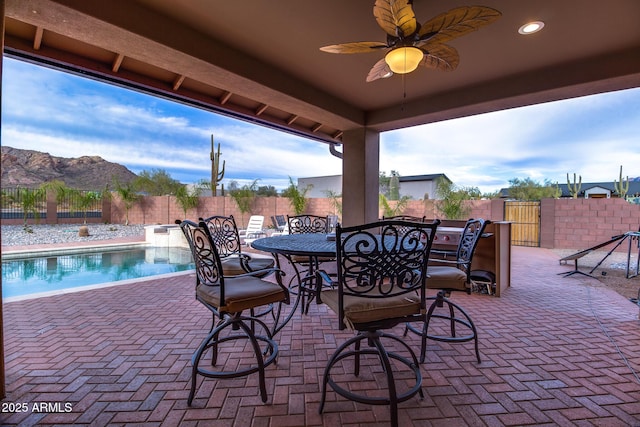 view of patio / terrace featuring ceiling fan, a fenced backyard, a mountain view, a fenced in pool, and outdoor dining space