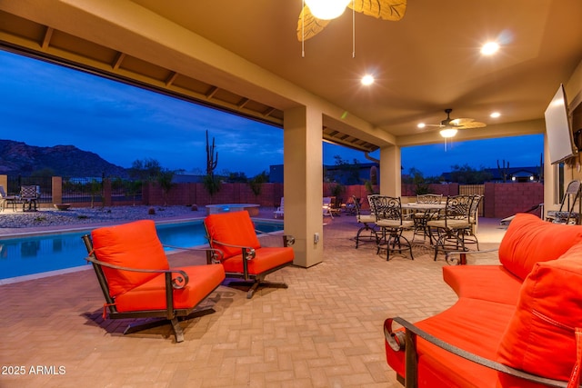 view of patio with a ceiling fan, a fenced in pool, a fenced backyard, a mountain view, and outdoor dining space