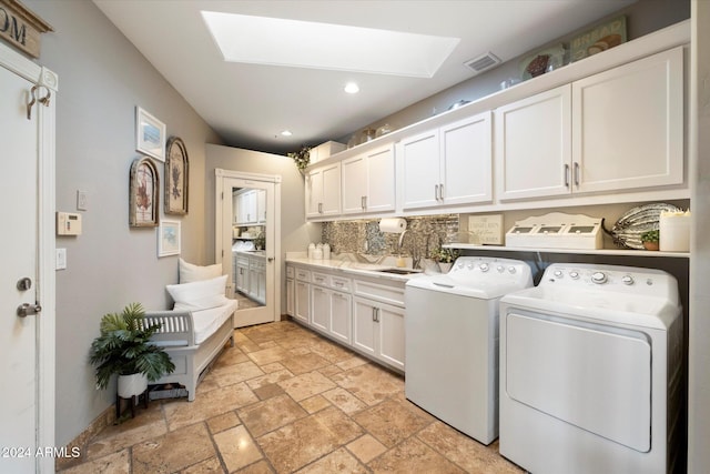 laundry room featuring washing machine and clothes dryer, a skylight, sink, and cabinets