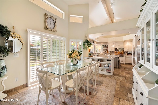 dining area with beam ceiling and high vaulted ceiling