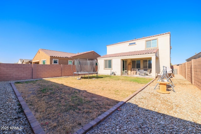 rear view of house with a trampoline and a patio