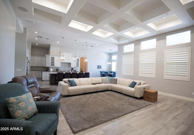 living room featuring light hardwood / wood-style flooring, beam ceiling, and coffered ceiling