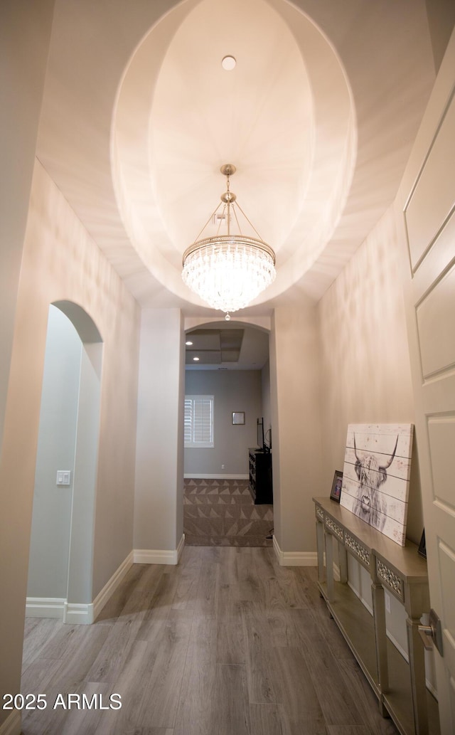 hall featuring an inviting chandelier, a tray ceiling, and hardwood / wood-style flooring