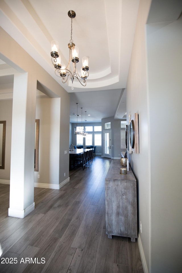 interior space with dark hardwood / wood-style floors, a raised ceiling, and a chandelier