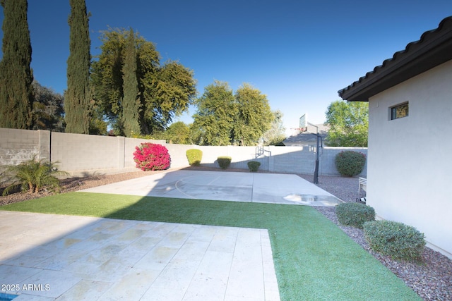 view of yard featuring basketball hoop and a patio