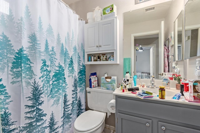 bathroom with walk in shower, ceiling fan, vanity, and toilet