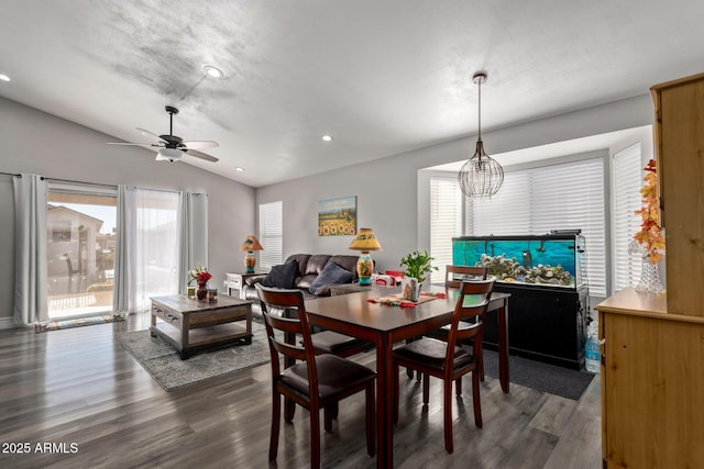 dining space with dark wood-type flooring, ceiling fan with notable chandelier, and vaulted ceiling