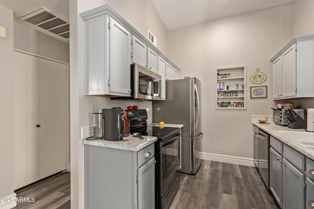 kitchen with sink, dark wood-type flooring, stainless steel appliances, and gray cabinets