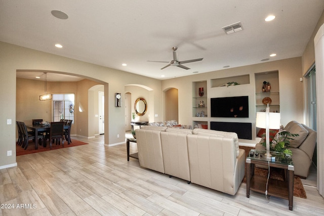 living room with ceiling fan, light hardwood / wood-style floors, and built in features