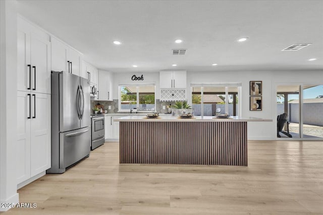 13215 N 30th Pl, Phoenix, AZ 85032 - kitchen featuring appliances with stainless steel finishes, white cabinets, light wood-type flooring, light countertops, and decorative backsplash