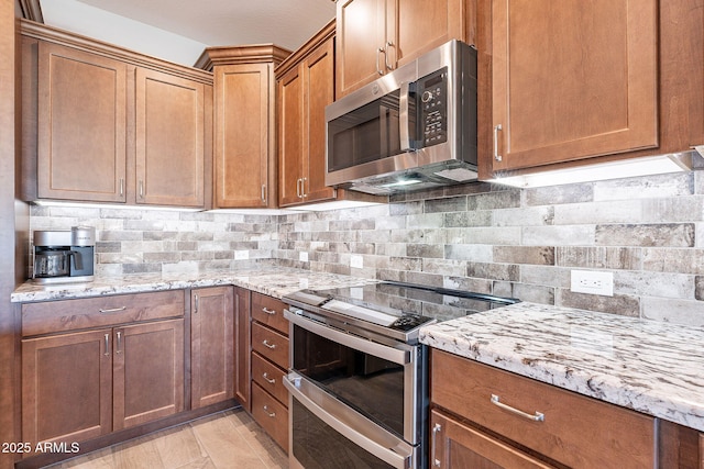 kitchen featuring backsplash, light stone counters, and stainless steel appliances