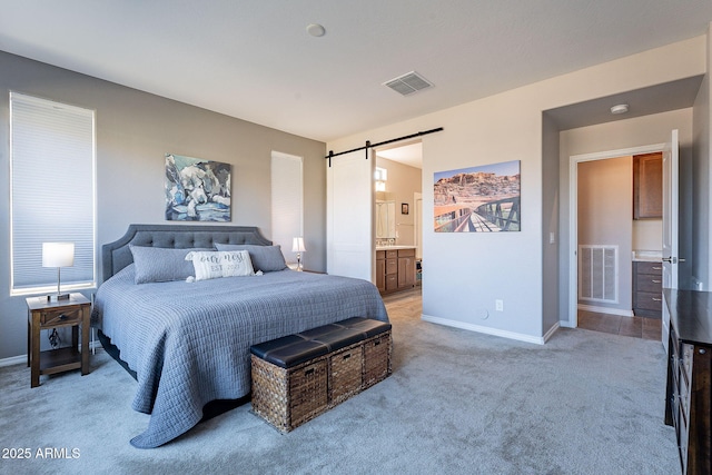 carpeted bedroom featuring ensuite bath and a barn door