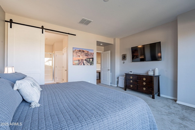 bedroom with connected bathroom, a barn door, and carpet flooring