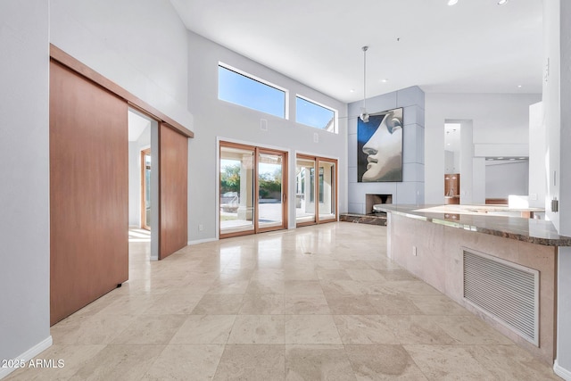 kitchen with a towering ceiling, a large fireplace, dark stone countertops, and decorative light fixtures