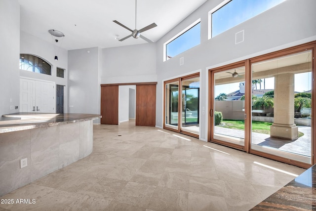 kitchen featuring a towering ceiling, ceiling fan, and stone countertops