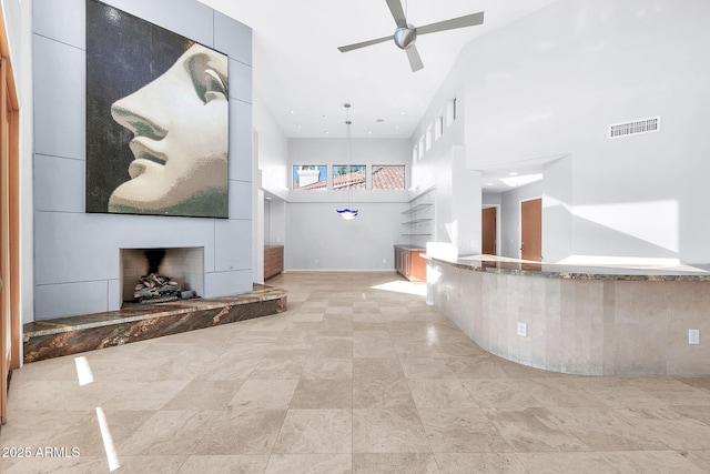 interior space featuring a towering ceiling, a large fireplace, and ceiling fan