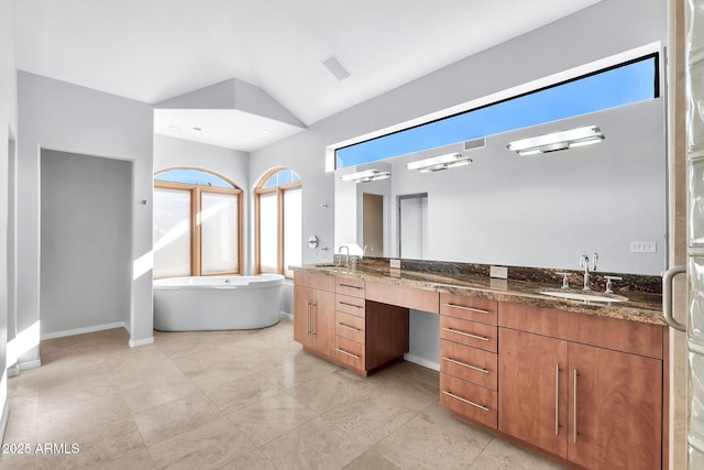 bathroom with lofted ceiling, a tub to relax in, and vanity