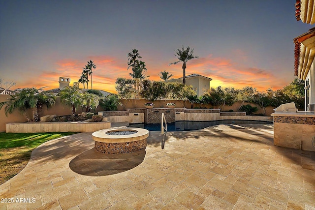 patio terrace at dusk with an outdoor kitchen and a fire pit