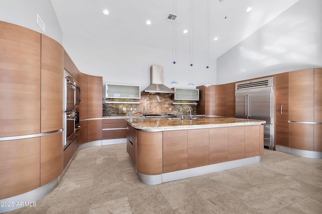 kitchen with pendant lighting, a large island, ventilation hood, and built in fridge