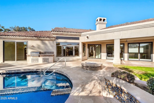 back of house with area for grilling, an outdoor fire pit, and a patio